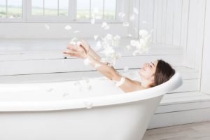 happy-female-throwing-petals-lying-bathtub_23-2147835571